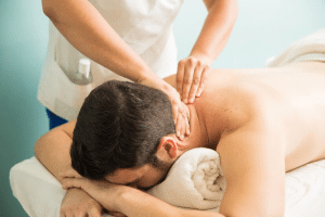 A masseur applying pressure to a client's back during a massage session.