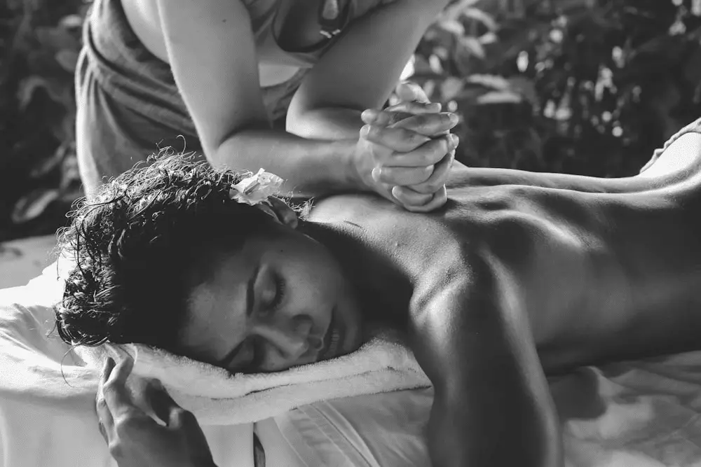 A black and white photo of a person receiving a deep tissue back massage from a massage therapist.