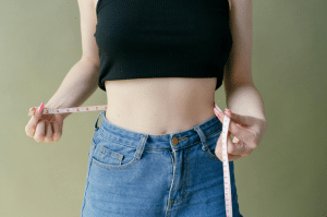 A woman measuring her waist.