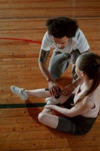 A man putting a kinesio tape on a woman's injured knee