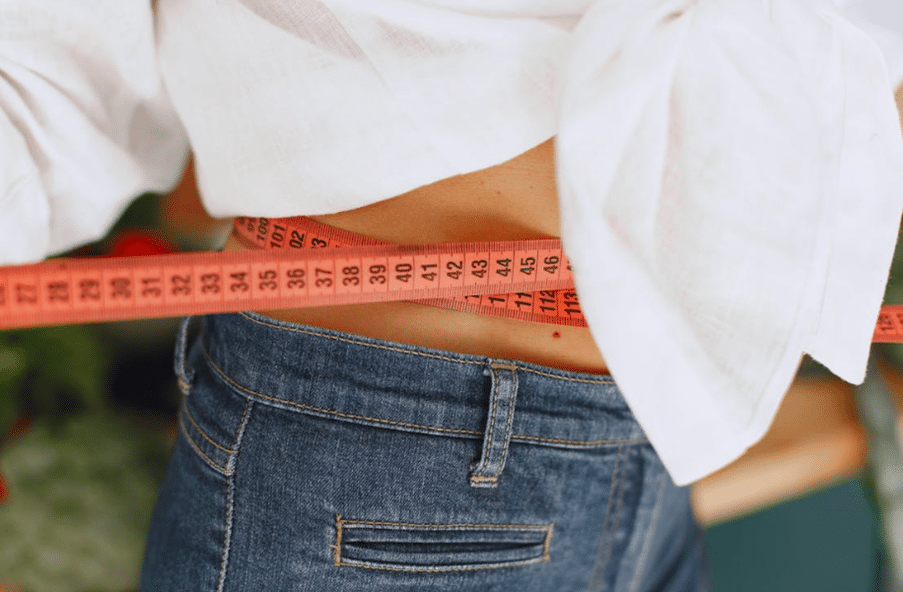 A woman measuring her waist.