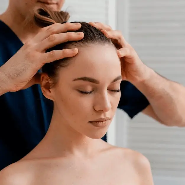 A woman with her eyes closed, enjoying a relaxing scalp massage.
