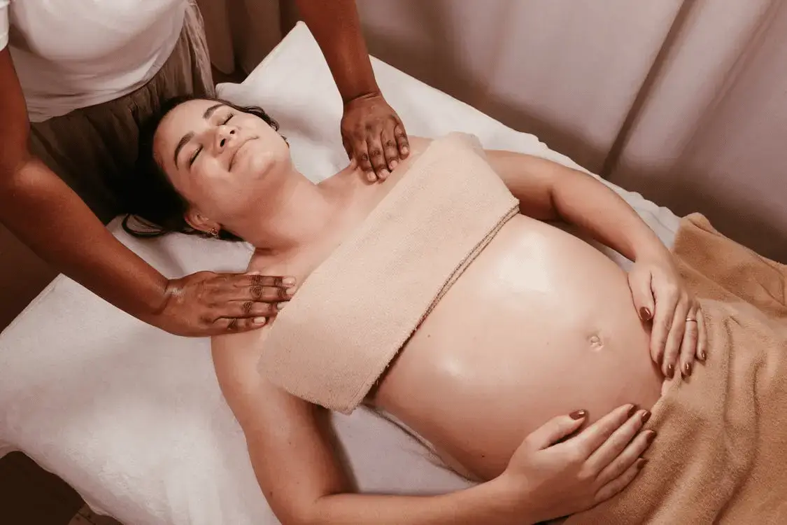 pregnant woman lying down for a prenatal massage and holding her belly