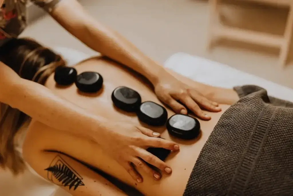 woman with a tattoo lying upside down with hot stones on her back