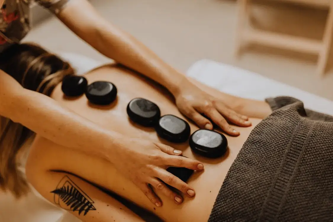 woman with a tattoo lying upside down with hot stones on her back