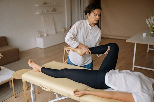 masseuse giving a leg massage to an athlete while they lie on the massage chair