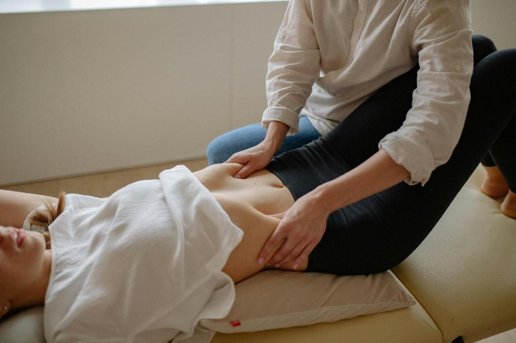 Massage therapist applying gentle abdominal massage to support relaxation, circulation, and seasonal wellness during autumn.