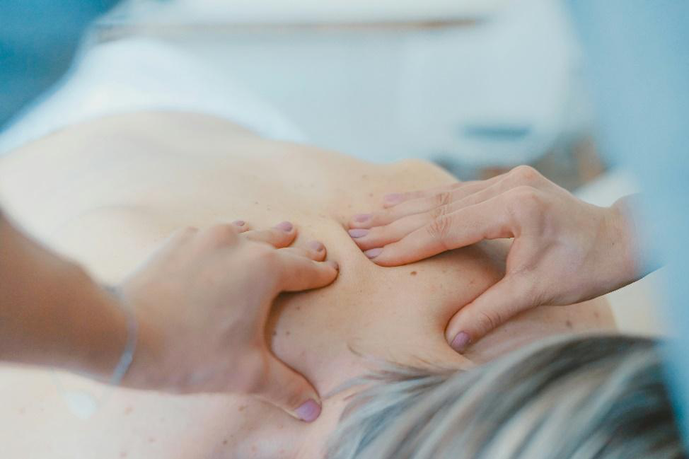 Massage therapist applying deep pressure to an athlete’s upper back muscles.