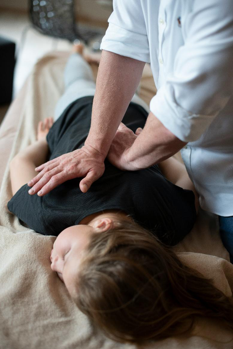 Massage therapist pressing into a client’s upper back for muscle relief.
