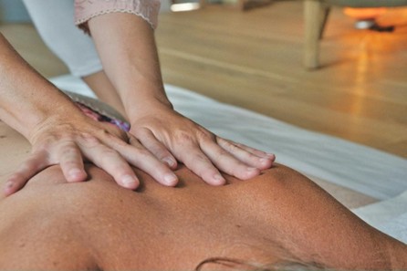 Massage therapist applying firm pressure along a client’s upper back to stimulate circulation and support immune system function.
