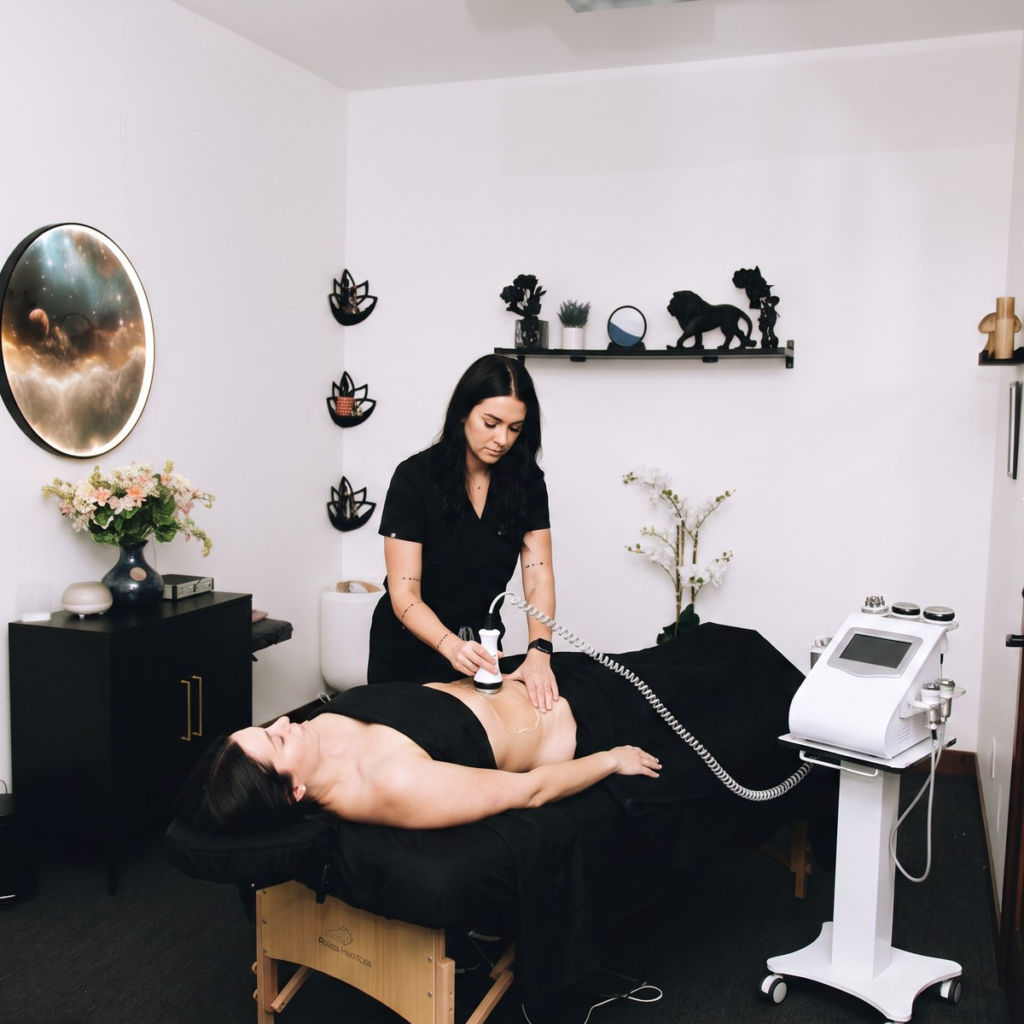 Therapist using gentle touch on a client’s lower leg in a red floral Master of Massage treatment room in Minneapolis